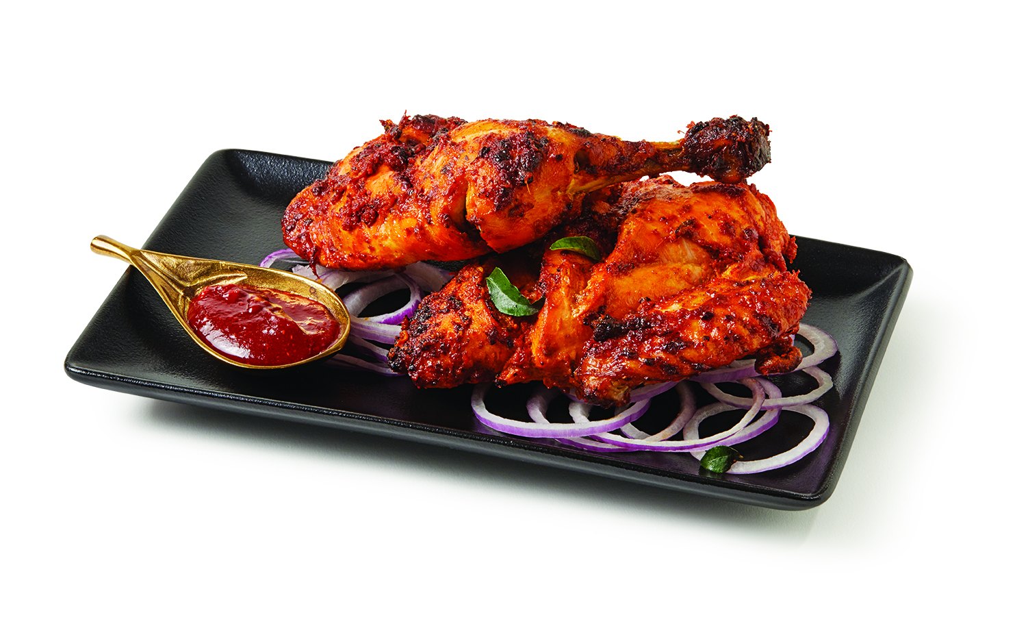 Tandoori chicken on a black plate with onion rings and house chutney